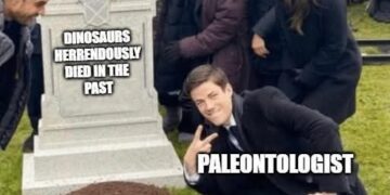 Paleontologist kneeling and smiling next to a tombstone that reads DINOSAURS HERRENDOUSLY DIED IN THE PAST