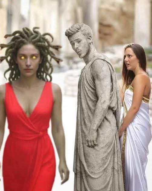 Woman in red dress standing next to a statue of Medusa