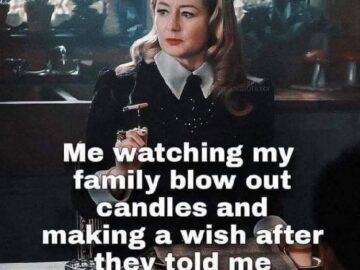 Woman in gothic style giving side-eye while family blows out birthday candles