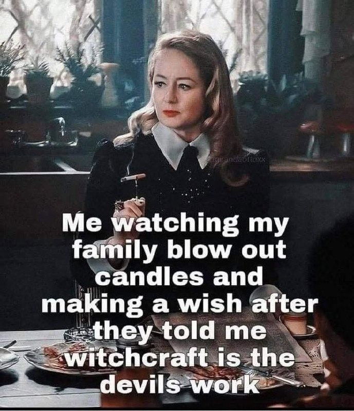 Woman in gothic style giving side-eye while family blows out birthday candles